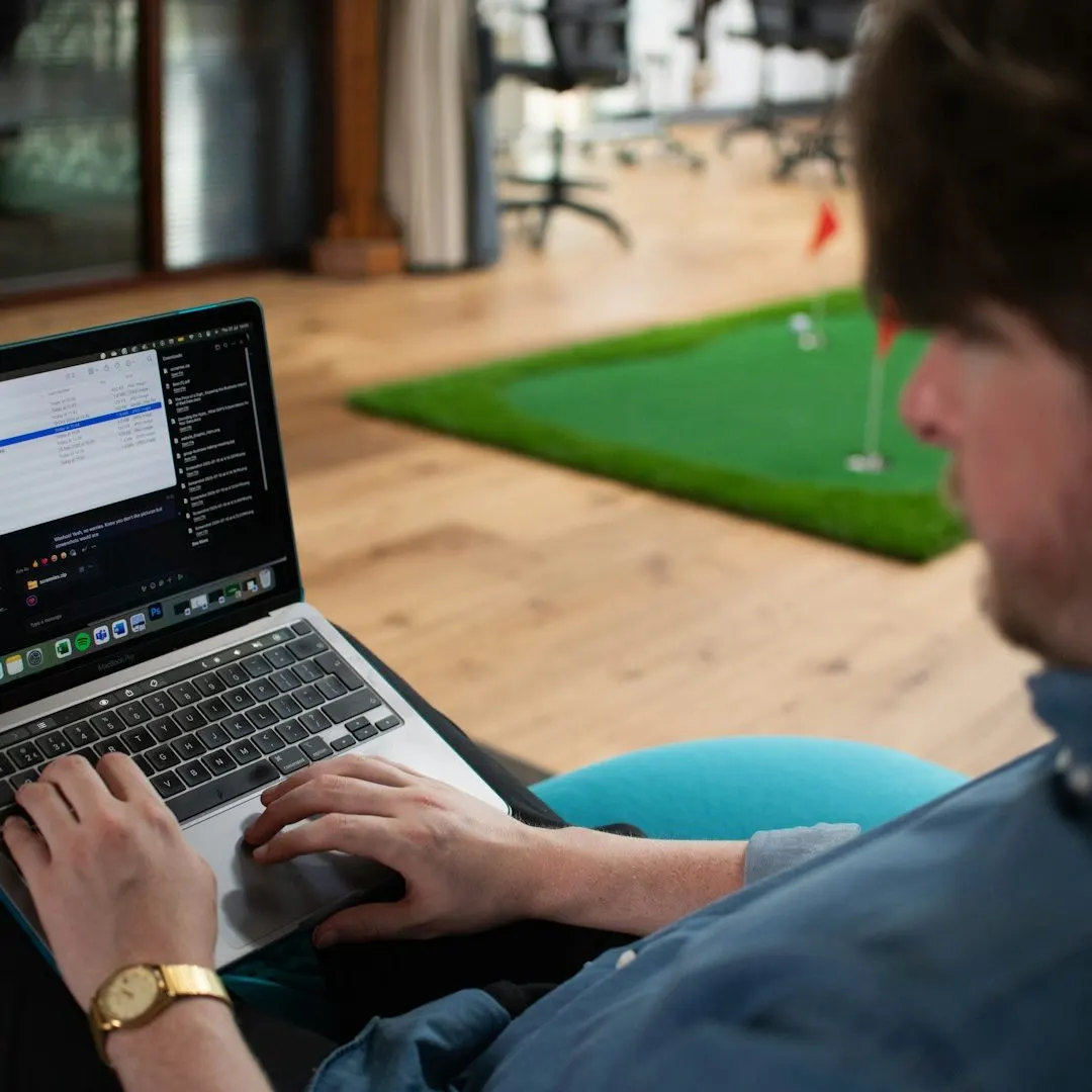 Golfeur qui travaille sur son ordinateur devant un tapis de putting